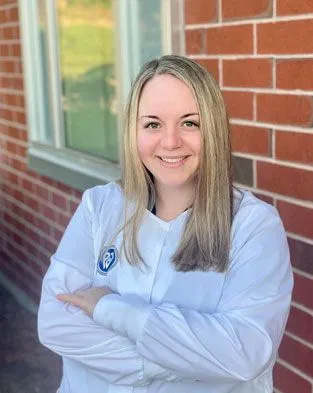 A person standing with arms crossed against a brick wall.