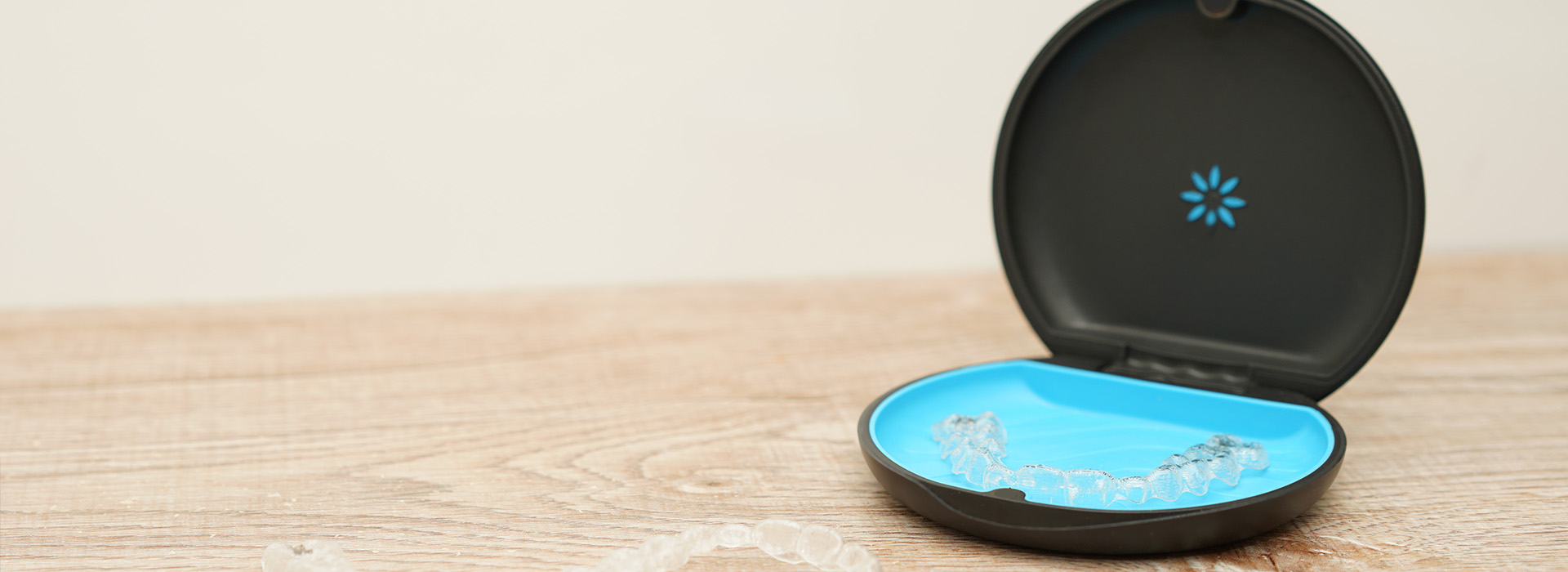 A small round black object with a blue interior, possibly a container or lid, placed on a wooden surface.