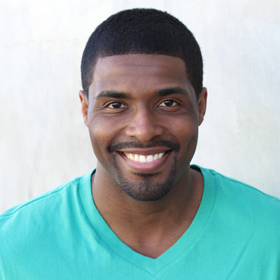 An elderly couple smiling at the camera outdoors.
