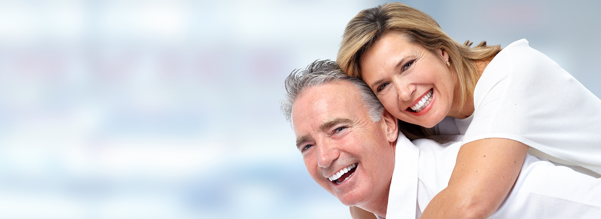 A man and woman are smiling at the camera while posing together with their arms around each other.