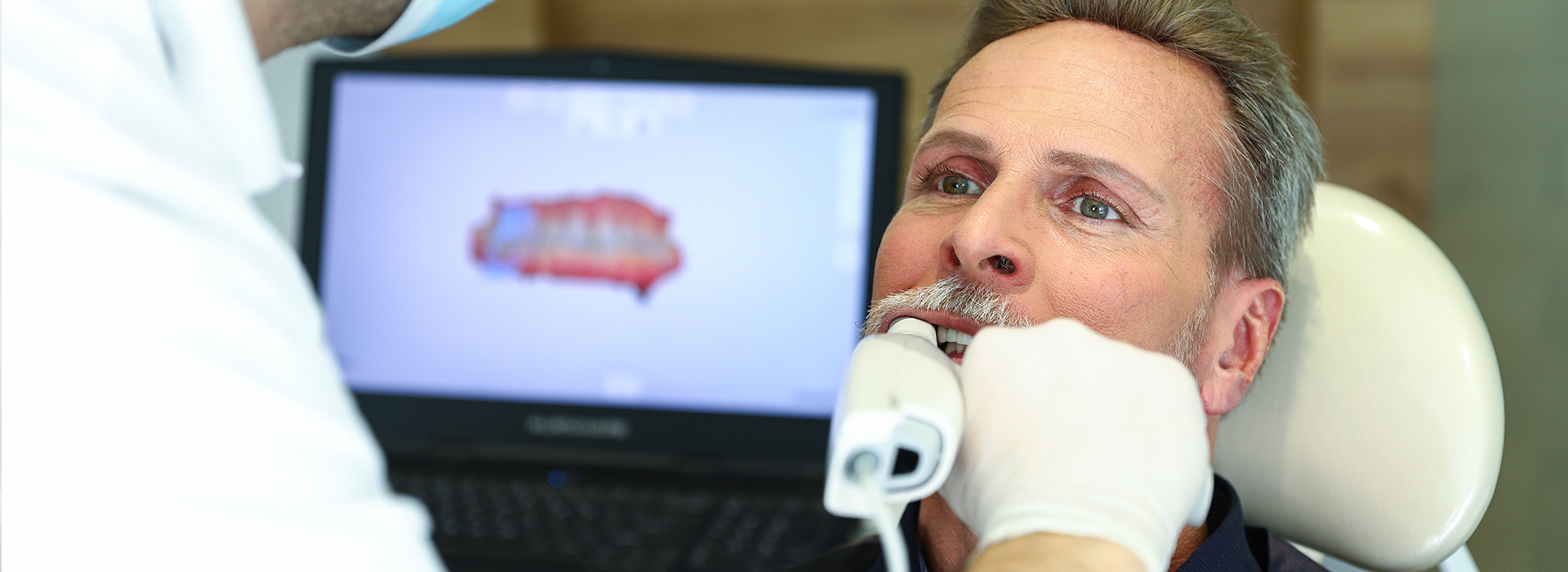 A man receiving dental care with a medical professional assisting him.