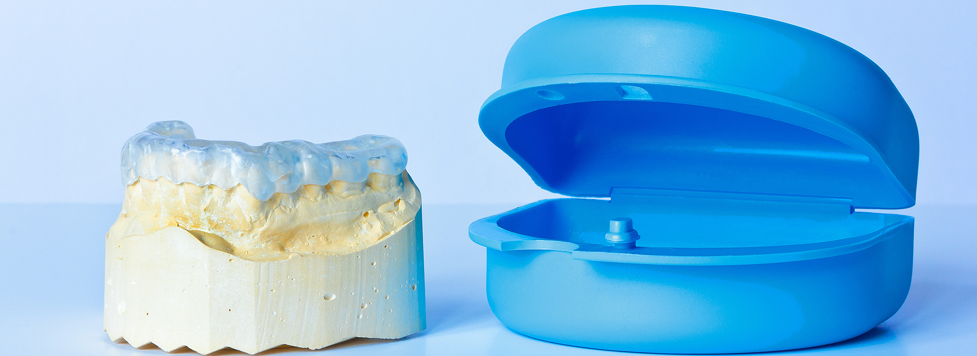 The image shows a blue dental implant fixture with a yellow disc-shaped object next to it, both placed on a white background.