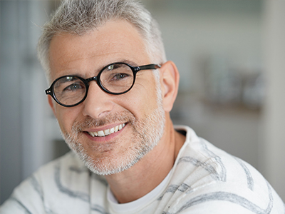 The image features a man with glasses smiling at the camera, displaying two different facial expressions in a split-screen format.
