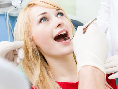 A woman undergoing dental treatment, with a dentist performing work on her teeth.