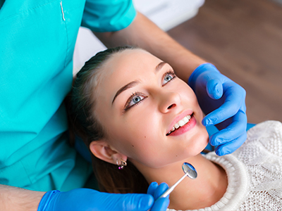 A young woman with a dental implant being fitted by a dental professional in a clinical setting.